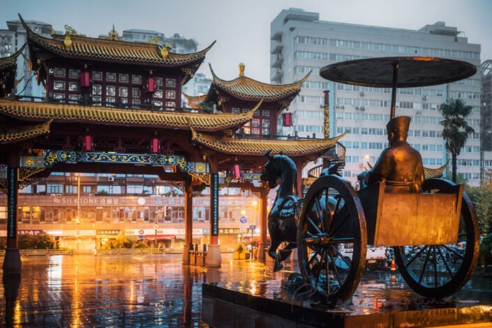 QinTailLu traditional Chinese gate and statue of Sima Xiangru Chinese ancient minister in a Chariot with a horse under the rain at dusk in Chengdu, Sichuan province, China