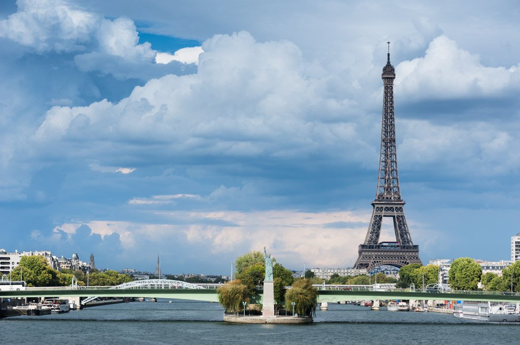 Paris - Eiffel tower, statue of liberty and river Seine with clouds on the background