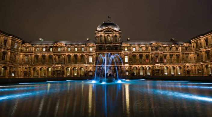 The Cour Carree of the Louvre at night with a blue fountain on the foreground, Paris, France