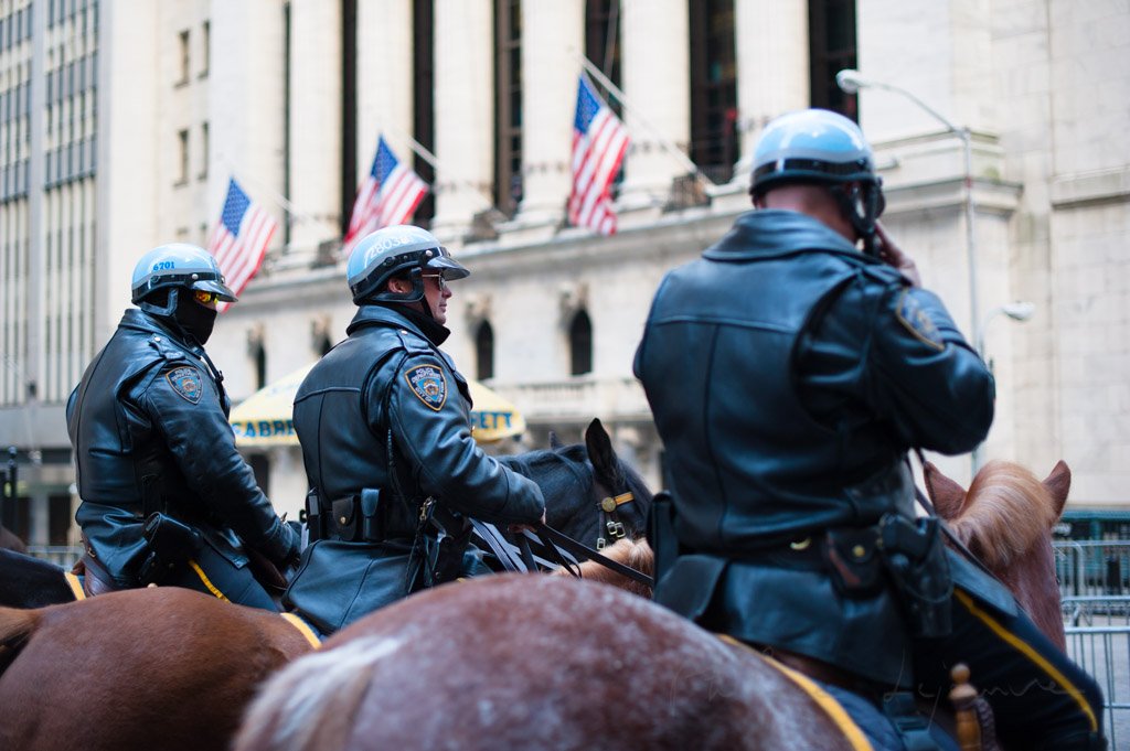 Three policemen on horses in front of the New York Stock Exchange building, New York City, USA