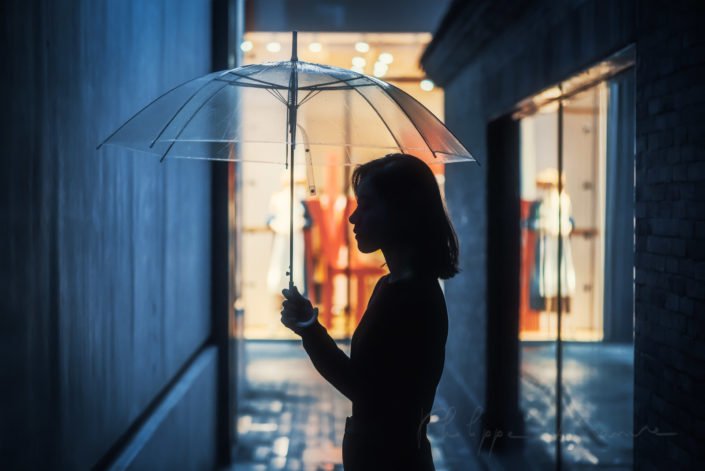 Young Chinese woman silhouette with an umbrella in a street at night, Chengdu, Sichuan province, China