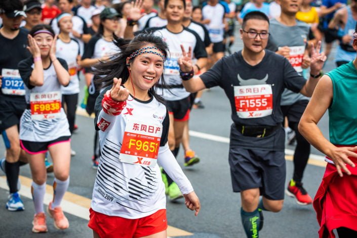 Chengdu, Sichuan province, China - Oct 27, 2019 : Young woman running at the Chengdu marathon and doing the chinese love sign