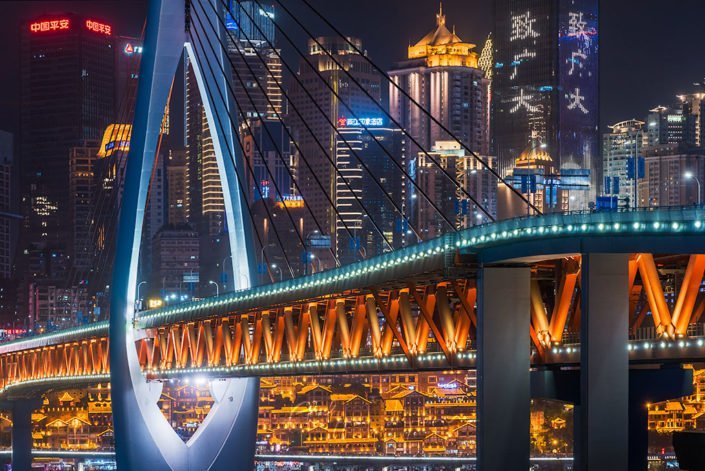 Chongqing illuminated skyline behind cable bridge at night, China