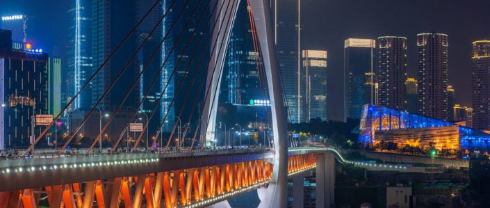 Chongqing illuminated skyline behind cable bridge at night, China