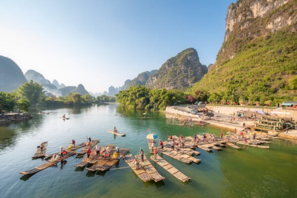 Tourist bamboo rafts arriving at the end of the tour on the river with karst limestone hills and blue sky in the background., Yangshuo, Guilin, Guangxi province, China