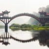 Ancient traditional chinese bridge in the fog in Leshan giant buddha touristic area - Chengdu, Sichuan Province, China