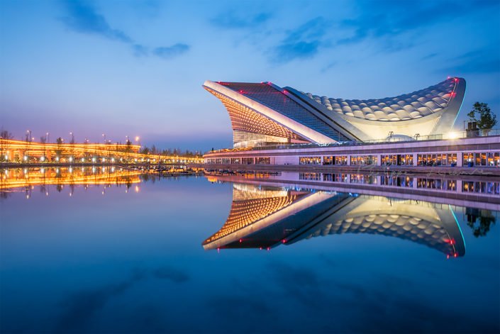 Chengdu open air music park modern building with futuristic architecture reflecting in a pond at blue hour, Sichuan province, China