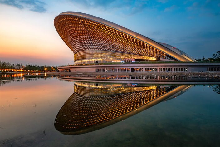 Chengdu open air music park modern building with futuristic architecture reflecting in a pond at blue hour, Sichuan province, China