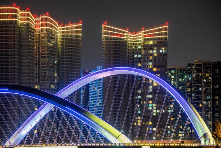 Arch cable bridge against skyscrapers illuminated at night in Chengdu, Sichuan province, China