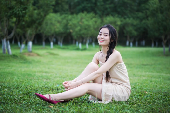 Chinese young woman sitting on grass in nature in Chengdu, Sichuan province, China