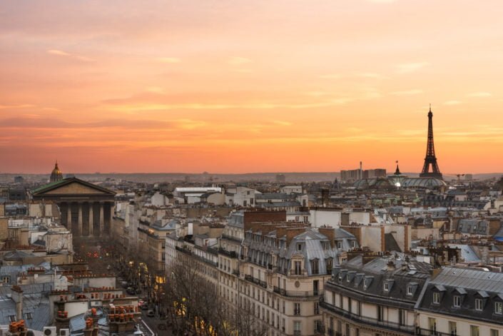 Eiffel tower, roofs and city skyline in Paris, France at sunset