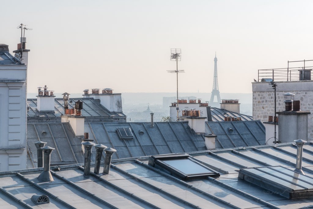 Distant view of the Eiffel tower from rooftops on a sunny day in Paris, France