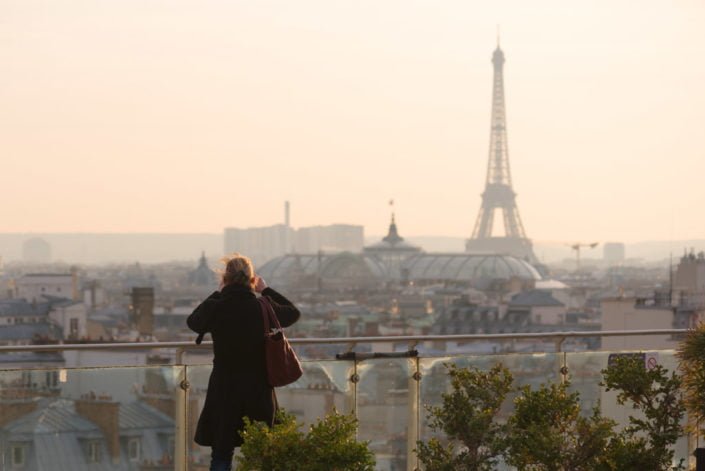 Woman taking the Eiffel tower in photo from an elevated point of view in Paris, France