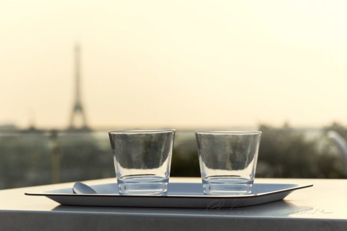 Two glasses on a plate with the Eiffel tower in the background in Paris, France.
