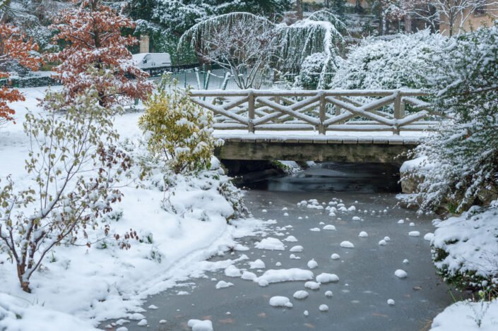 Frozen stream and little bridge under the snow in winter in the Trocadero gardens in Paris, France