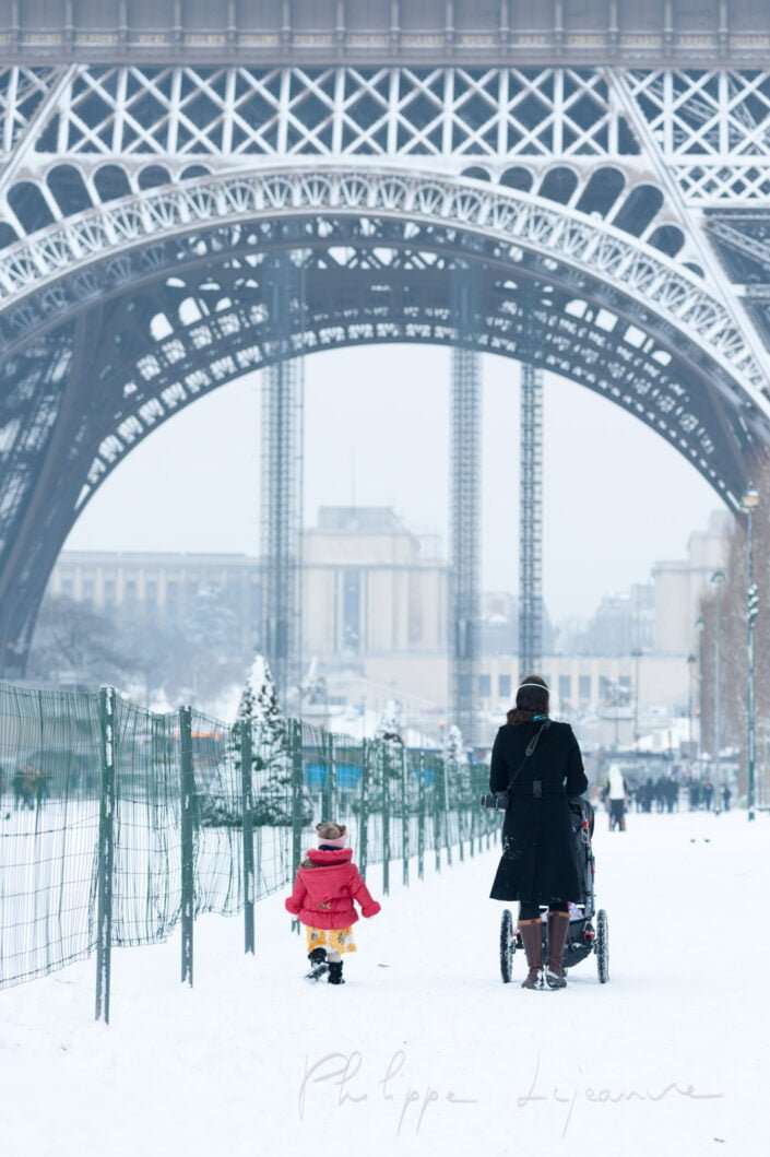 A woman and her little girl walking by the Eiffel tower in the snow in winter, Paris, France