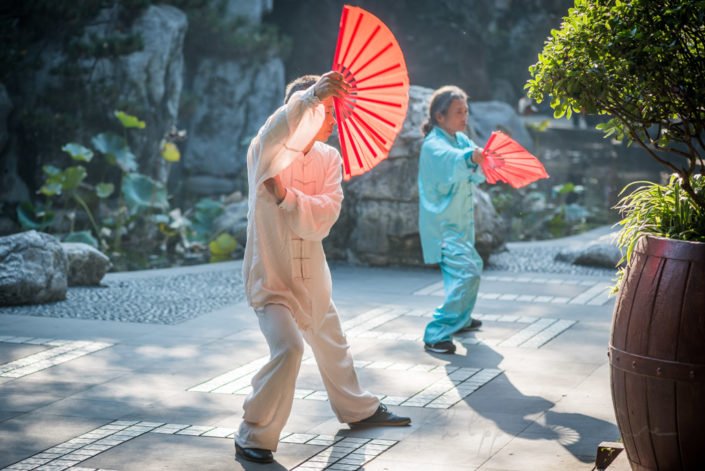 Chengdu, Sichuan province, China : Man and woman practising Tai with red fans in the morning in People's park.