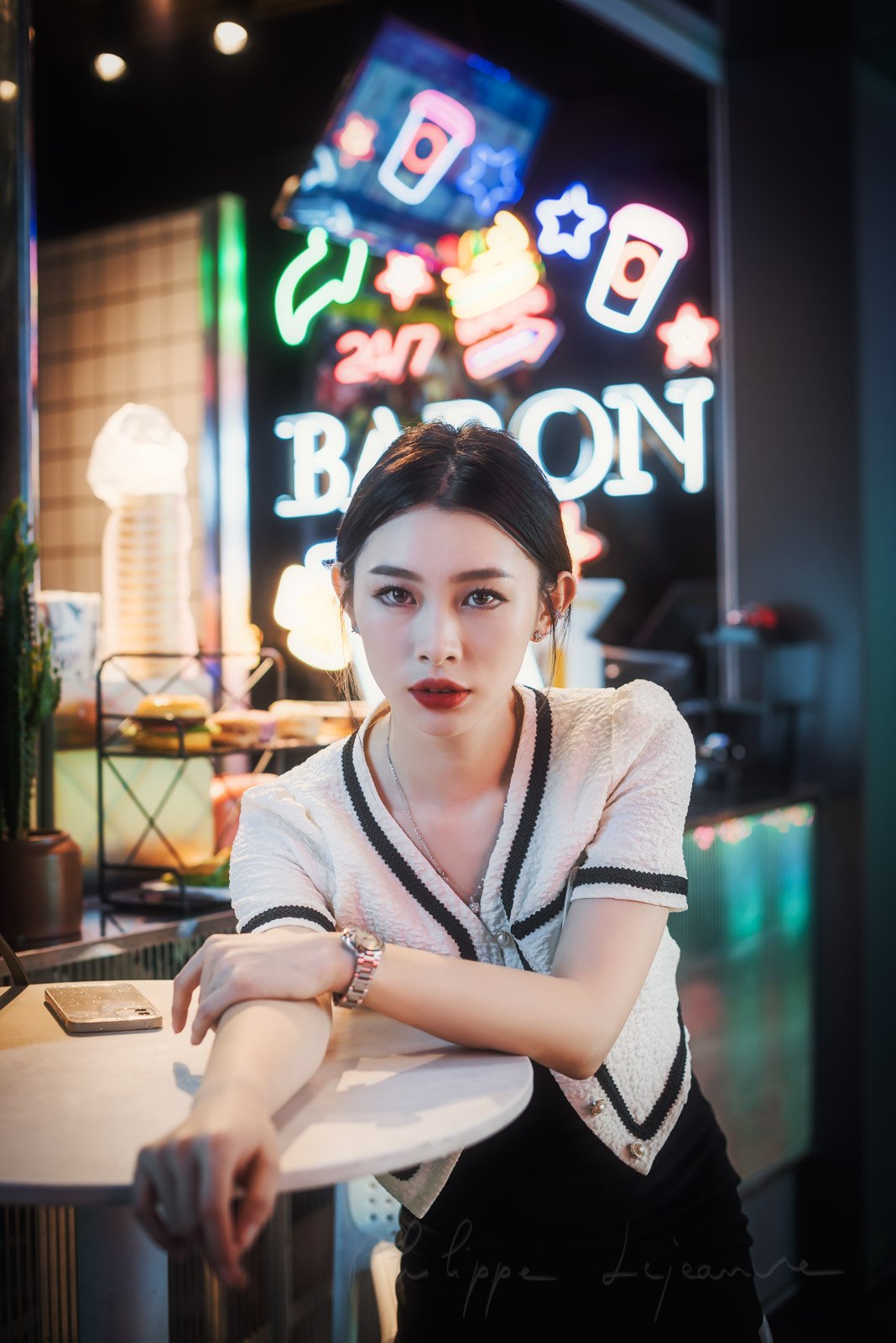 Young chinese woman sitting at a table with neon lights in the background in Chengdu, Sichuan province, China