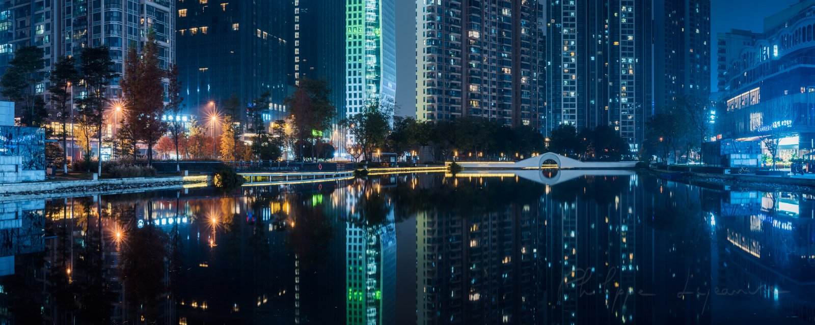 Illuminated skycrapers reflecting in a pond panorama at night in Chengdu, Sichuan province, China