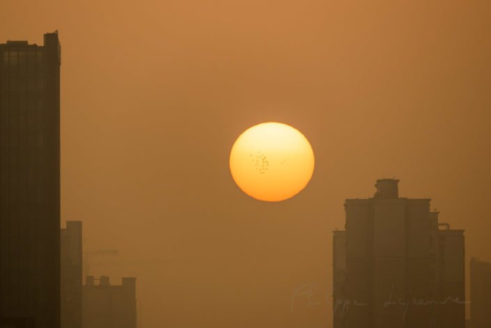 Sun rising behind building in the fog in Chengdu, Sichuan province, China