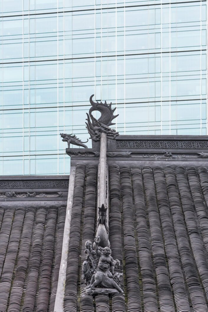 culptures on the roof of Dacishi Temple against modern building