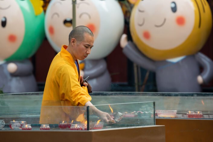 Buddhist monk handling a candle in Daci Buddhist temple, Chengdu, Sichuan Province, China