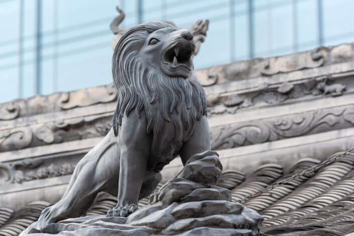 Lion sculpture on Daci buddhist temple roof against modern building in Chengdu, China