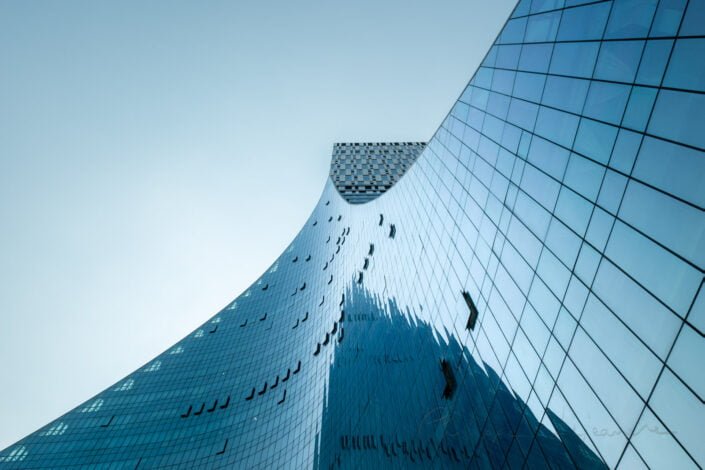 CCEC Modern curved glass building facade reflecting clear blue sky in Chengdu, Sichuan province, China