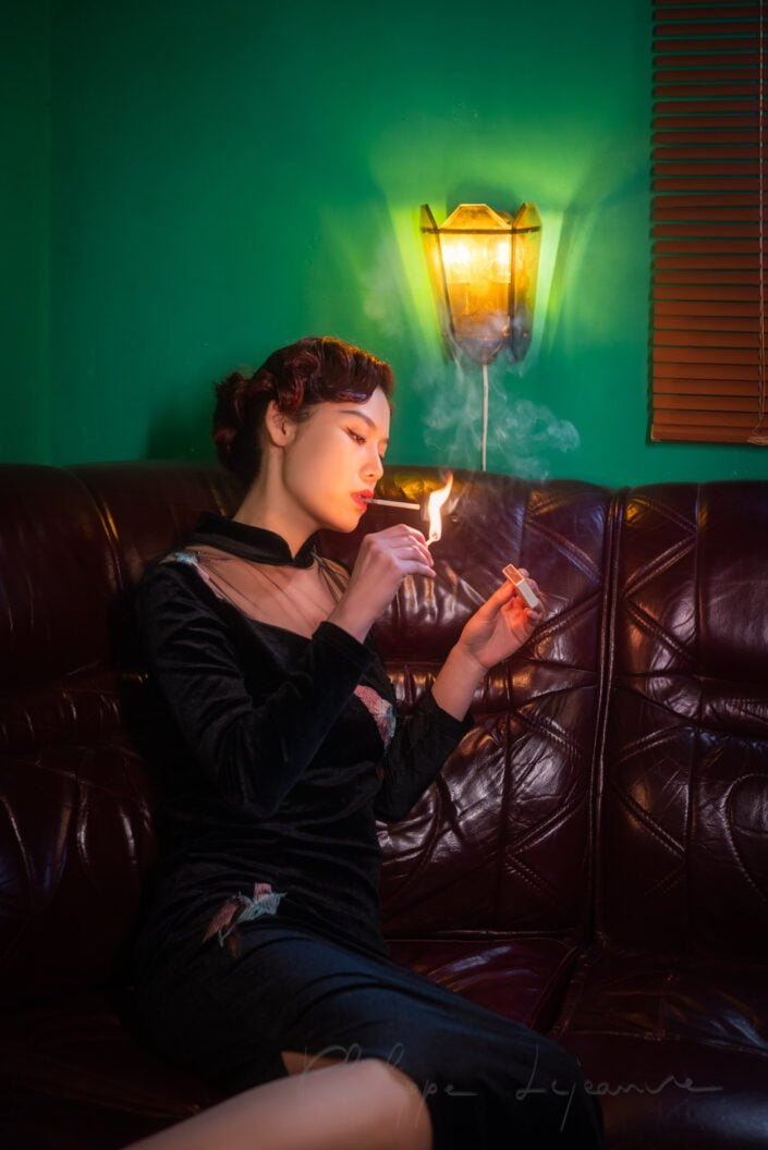 Young woman on a lether couch lighting a cigarette, Chengdu, Sichuan province, China