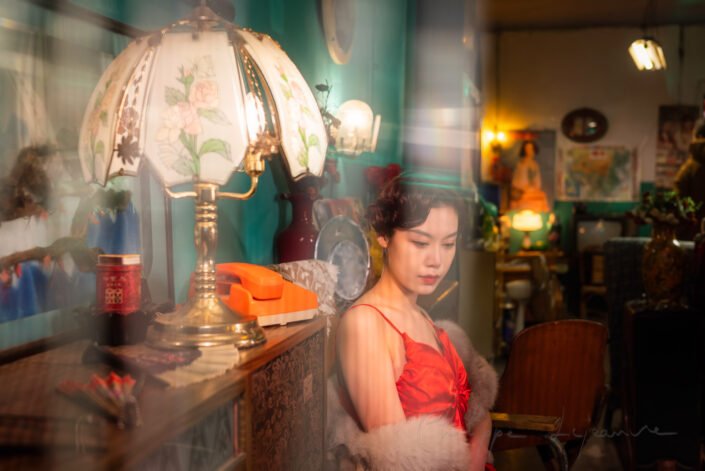 Young woman with a red dress sitting behind a curtain vintage portrait, Chengdu, Sichuan province, China