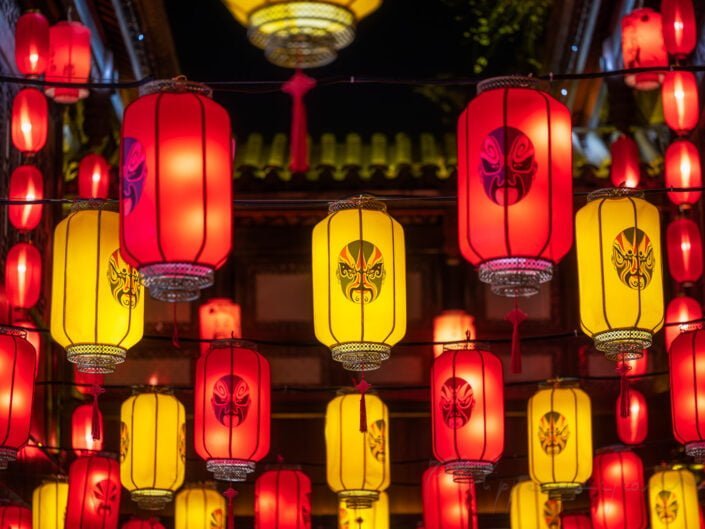 Red and yellow Chinese lanterns with Sichuan opera faces illuminated at night, Chengdu, Sichuan province, China