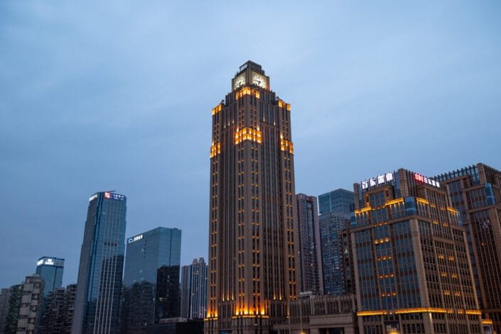 Chengdu city at dusk or night with skyscrapers lit up and a clock tower in the center of the skyline